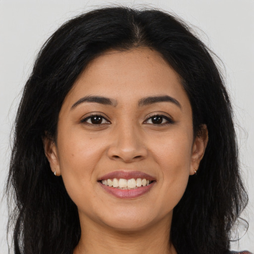 Joyful latino young-adult female with long  brown hair and brown eyes