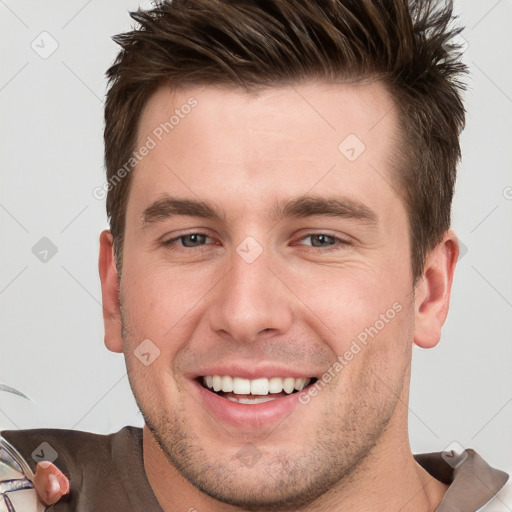 Joyful white young-adult male with short  brown hair and grey eyes