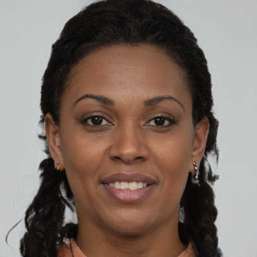Joyful black young-adult female with long  brown hair and brown eyes
