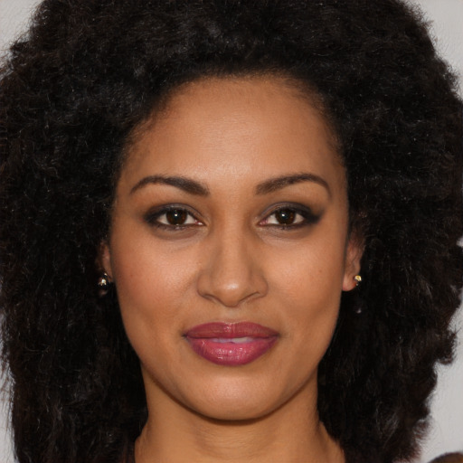 Joyful black young-adult female with long  brown hair and brown eyes