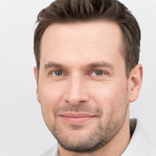 Joyful white young-adult male with short  brown hair and grey eyes