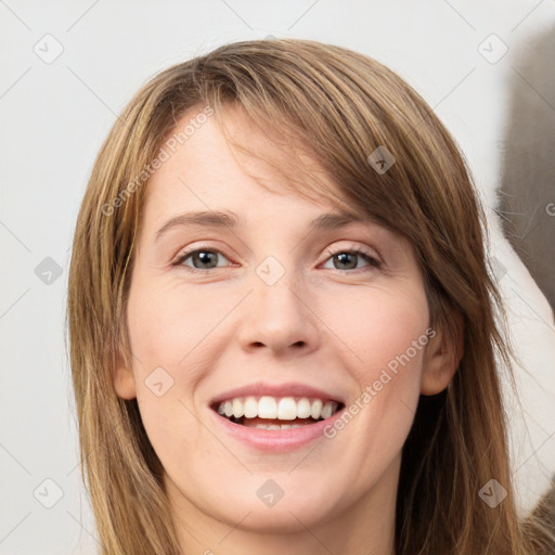 Joyful white young-adult female with long  brown hair and grey eyes