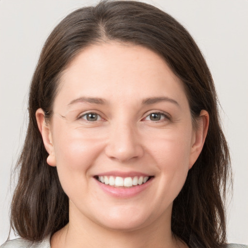 Joyful white young-adult female with long  brown hair and grey eyes