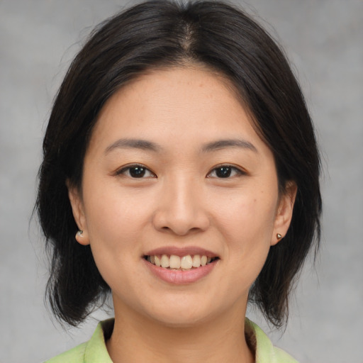 Joyful asian young-adult female with medium  brown hair and brown eyes