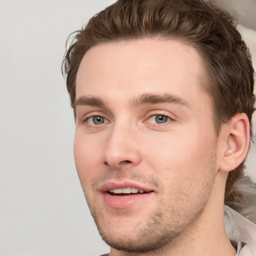 Joyful white young-adult male with short  brown hair and grey eyes