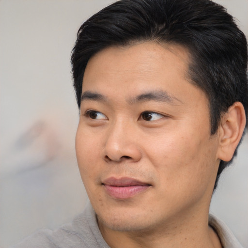 Joyful asian young-adult male with short  brown hair and brown eyes