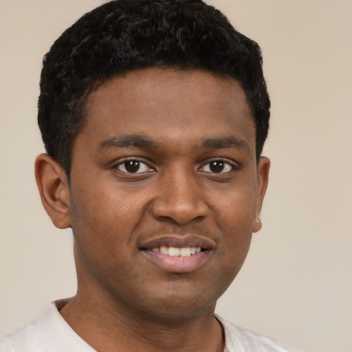 Joyful black young-adult male with short  brown hair and brown eyes