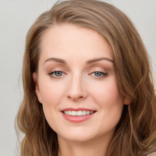 Joyful white young-adult female with long  brown hair and blue eyes