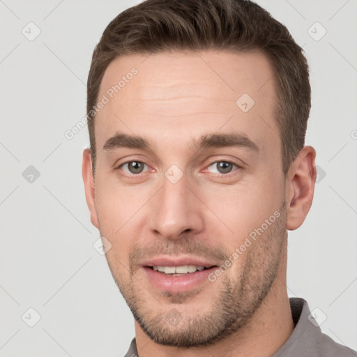 Joyful white young-adult male with short  brown hair and grey eyes