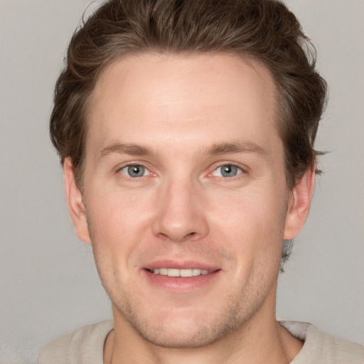 Joyful white young-adult male with short  brown hair and grey eyes