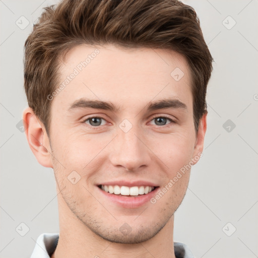 Joyful white young-adult male with short  brown hair and grey eyes