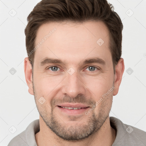 Joyful white young-adult male with short  brown hair and grey eyes