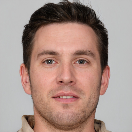 Joyful white young-adult male with short  brown hair and grey eyes