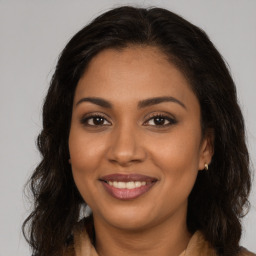 Joyful black young-adult female with long  brown hair and brown eyes