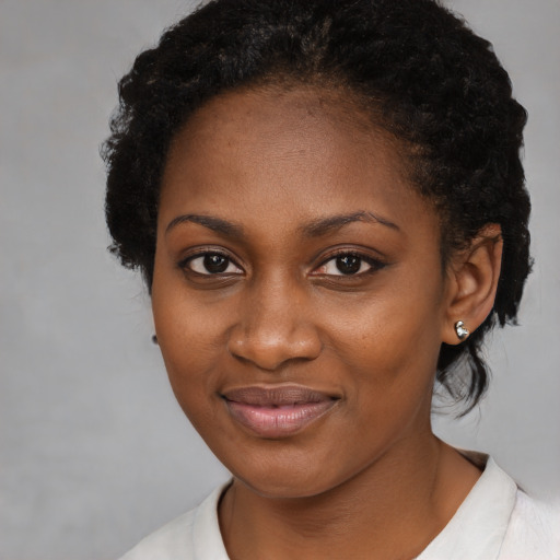 Joyful black young-adult female with short  black hair and brown eyes