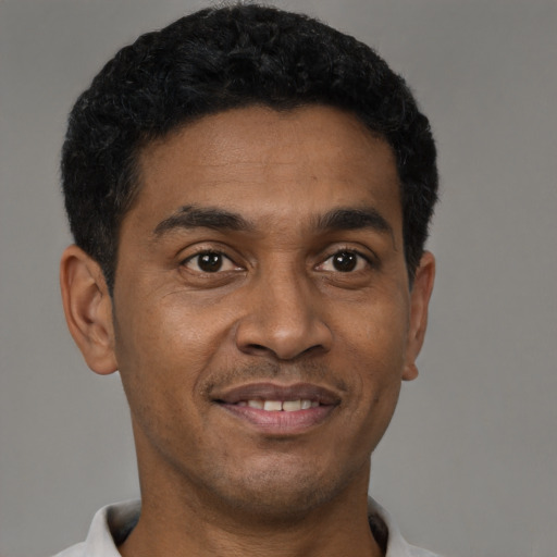 Joyful black young-adult male with short  black hair and brown eyes