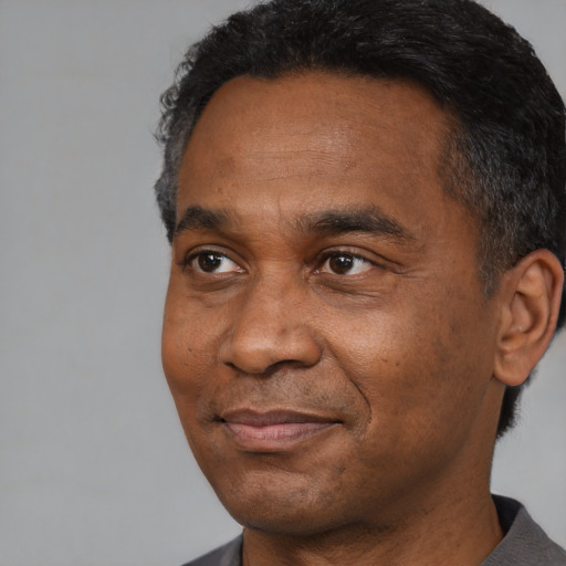 Joyful black adult male with short  black hair and brown eyes