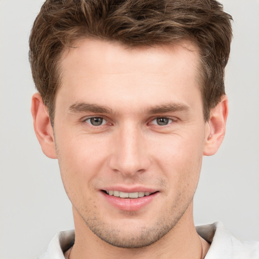 Joyful white young-adult male with short  brown hair and grey eyes