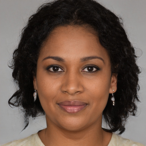 Joyful black young-adult female with long  brown hair and brown eyes
