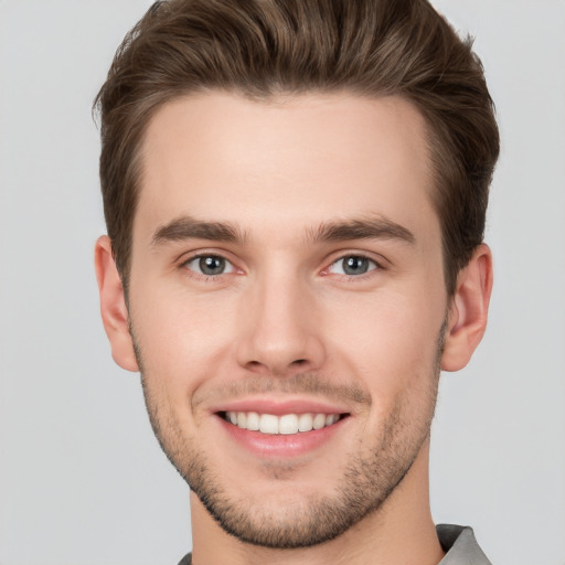 Joyful white young-adult male with short  brown hair and grey eyes