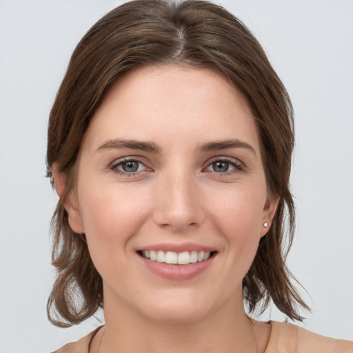 Joyful white young-adult female with medium  brown hair and grey eyes