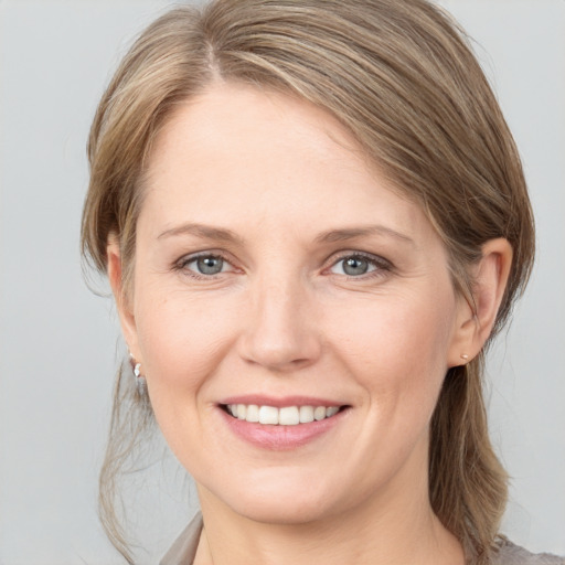 Joyful white young-adult female with medium  brown hair and grey eyes