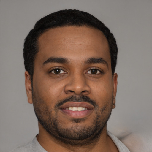 Joyful black young-adult male with short  brown hair and brown eyes