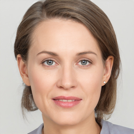 Joyful white young-adult female with medium  brown hair and grey eyes