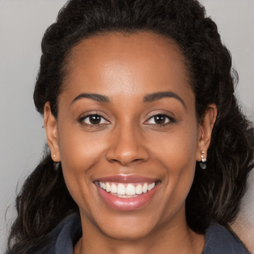 Joyful black young-adult female with long  brown hair and brown eyes