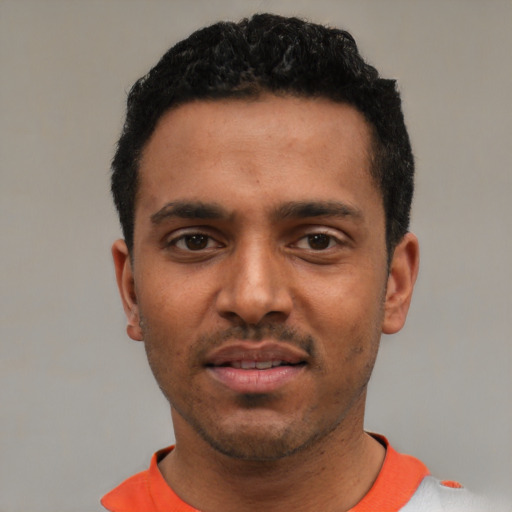 Joyful black young-adult male with short  black hair and brown eyes