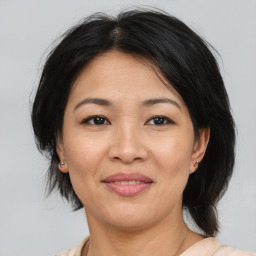 Joyful asian adult female with medium  brown hair and brown eyes