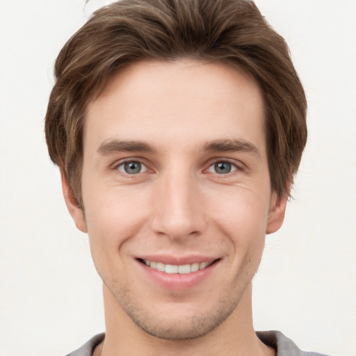 Joyful white young-adult male with short  brown hair and grey eyes