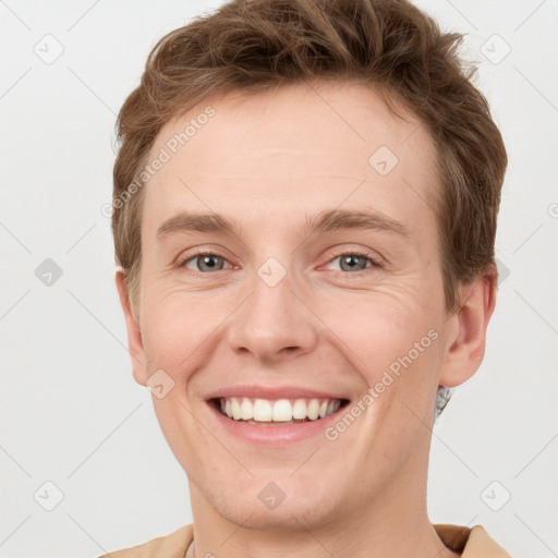 Joyful white young-adult male with short  brown hair and grey eyes