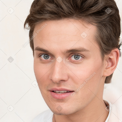 Joyful white young-adult male with short  brown hair and grey eyes