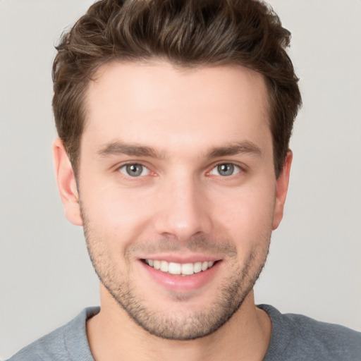 Joyful white young-adult male with short  brown hair and grey eyes