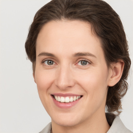 Joyful white young-adult female with medium  brown hair and grey eyes