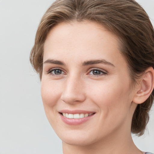 Joyful white young-adult female with medium  brown hair and grey eyes