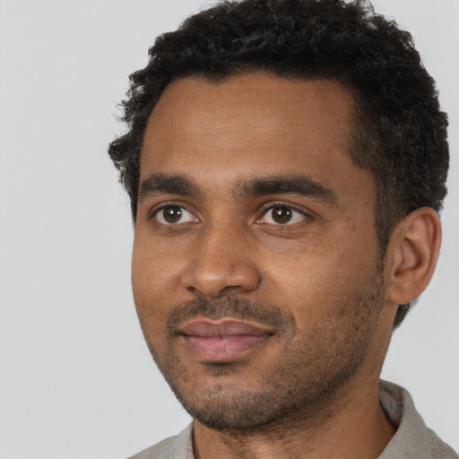 Joyful black young-adult male with short  black hair and brown eyes