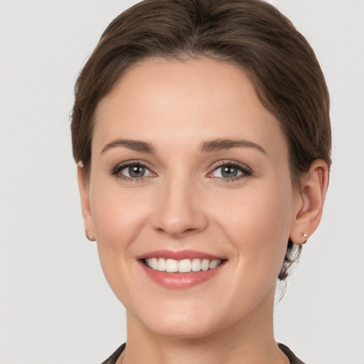 Joyful white young-adult female with medium  brown hair and grey eyes