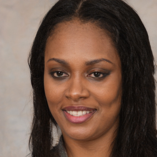 Joyful black young-adult female with long  black hair and brown eyes