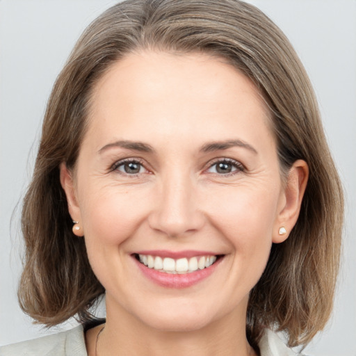 Joyful white young-adult female with medium  brown hair and grey eyes