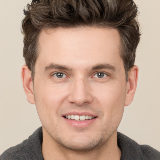 Joyful white young-adult male with short  brown hair and grey eyes