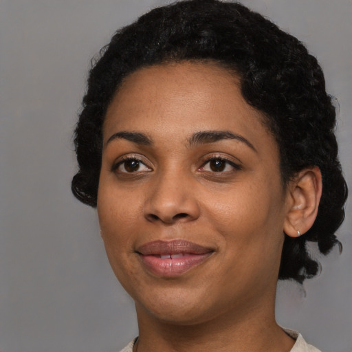 Joyful black young-adult female with short  black hair and brown eyes