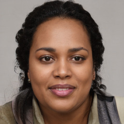 Joyful black young-adult female with long  brown hair and brown eyes