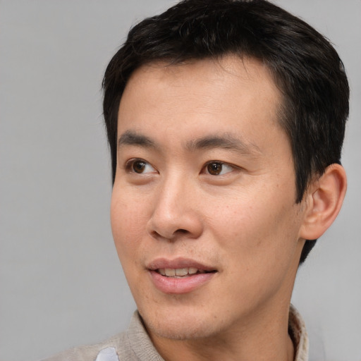 Joyful asian young-adult male with short  brown hair and brown eyes