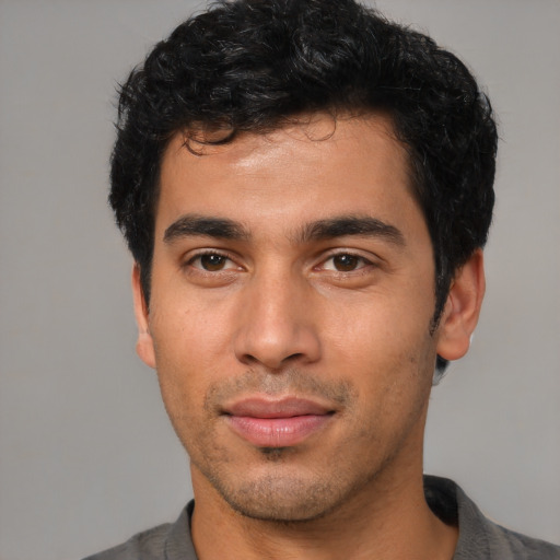 Joyful latino young-adult male with short  black hair and brown eyes