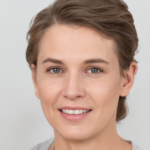 Joyful white young-adult female with medium  brown hair and grey eyes