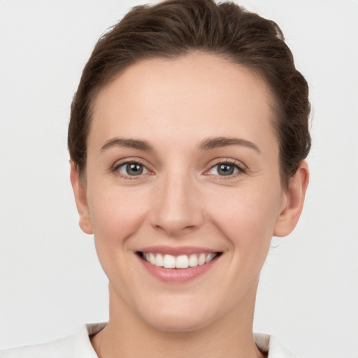 Joyful white young-adult female with short  brown hair and grey eyes