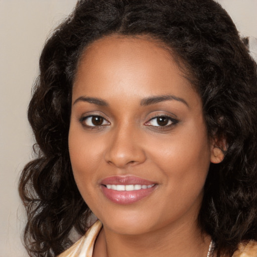 Joyful black young-adult female with long  brown hair and brown eyes