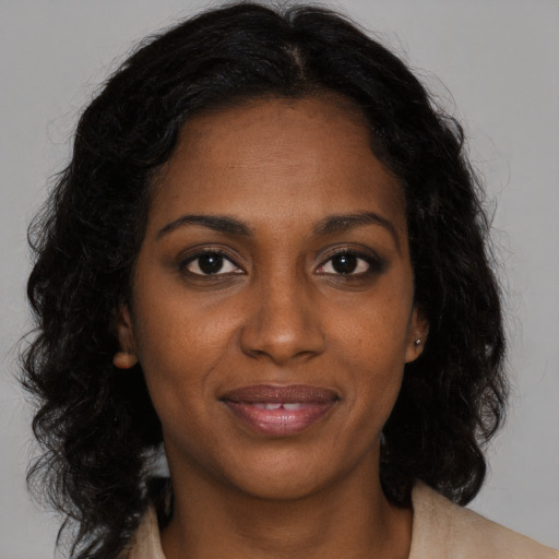 Joyful black young-adult female with long  brown hair and brown eyes